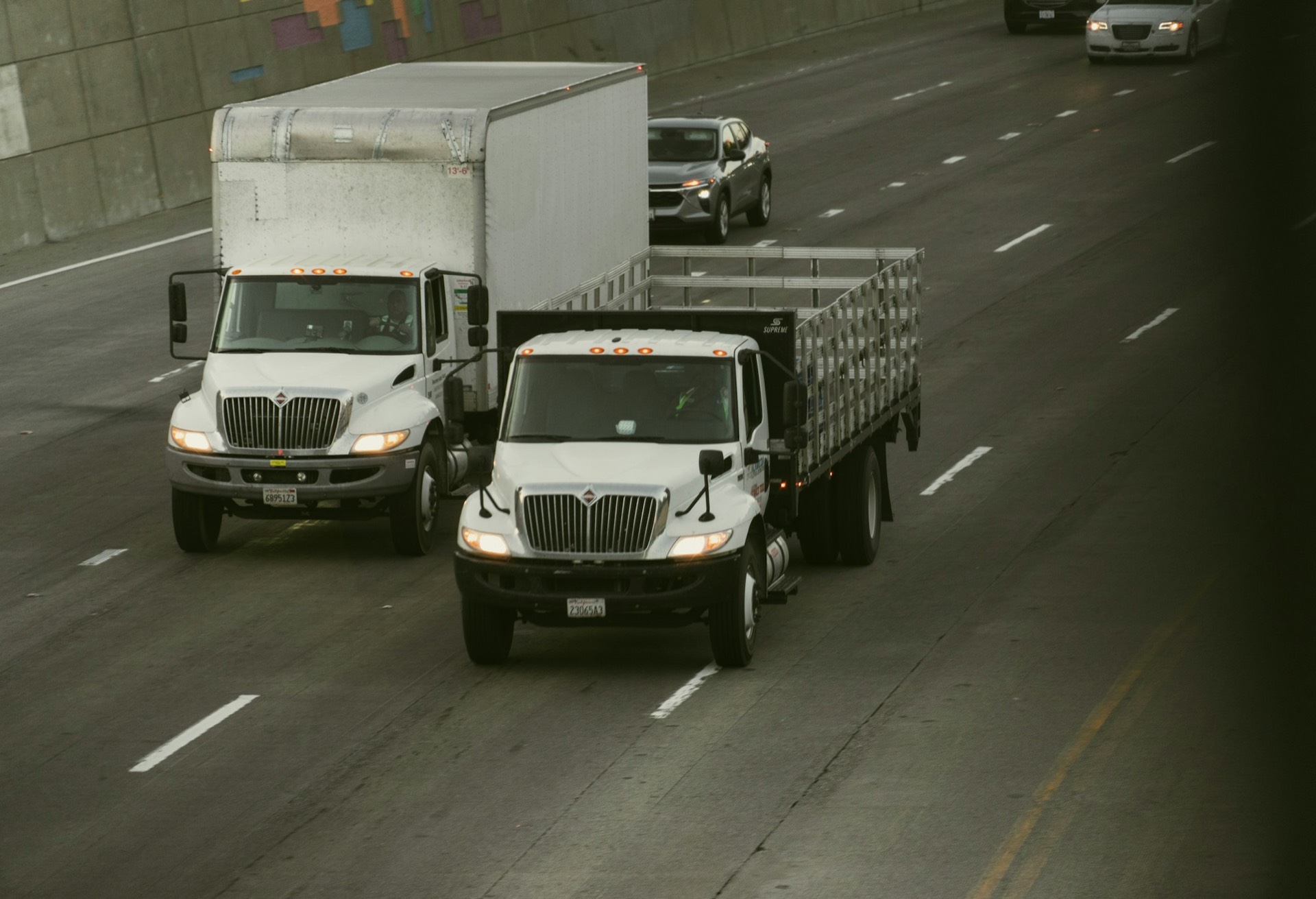 A box truck and flatbed delivery truck on an American highway